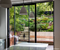 Full height view of the garden from the glass doors of the house kitchen, allowing tantalising glimpses through to the rear woodland, and upper deck area.