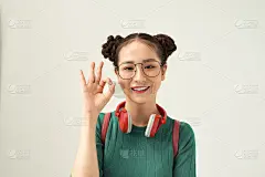 年轻的亚洲女学生戴眼镜和背包在孤立的背景做ok手势与手指，优秀的象征