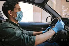 一名驾驶汽车的男子在疫情期间戴上医用口罩，一名出租车司机戴上口罩，保护自己免受病毒感染。白色汽车的司