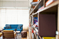 A long bookcase in a room with a sofa, a chair and a pouffe