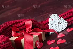 白色礼盒和大的心与红色的针织围巾在红色的木质背景。