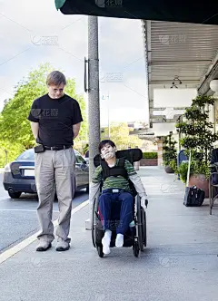 父亲陪着坐轮椅的残疾儿子穿过城镇