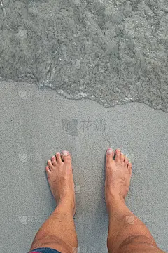 双脚踩在灰色的沙滩上