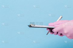 一只戴着粉色医用手套的女性手拿着一张蓝色背景的空白纸。模拟，名片