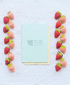 一个浅绿色卡片的模型被放置在红白草莓牌之间，在白色蓬松的布料背景上并排排列，垂直的