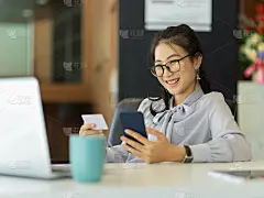 在办公室里用智能手机看名片的女商人