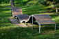设计一个波浪线形状的长凳。金属镀锌框架上的木质镶板。这张长椅在城市公园里对年轻人来说是不常见的，坐着
