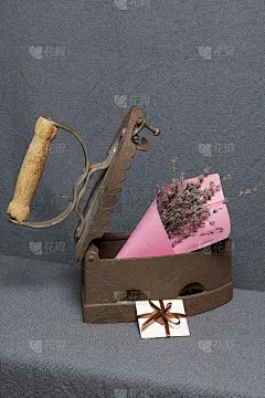 用热煤加热的旧铁。一束干花嵌在微微张开的铁器里。旁边是一张贺卡。