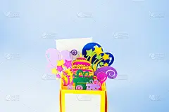 生日快乐手工弹出纸制贺卡。明亮的明信片与3D纸图的礼盒与生日蛋糕，礼物，气球和烟花内在蓝色的背景。本