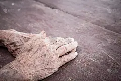 双手亚洲老年妇女紧握着她的手放在大腿上，一双老人布满皱纹的手和辛苦劳作的痕迹，世界善良老人和成人的关