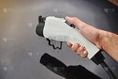 男人的手握电动车充电插头在一个黑暗的背景。环保替代能源概念。
