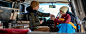 Un homme et une femme dans des vêtements d’hiver sont assis dans un véhicule et tiennent des tasses de camping contenant des boissons chaudes.