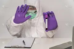 身穿防护服、戴口罩的医生手持新型冠状病毒(COVID-19)快速暴发血液检测阳性的结果，在家中举手阻