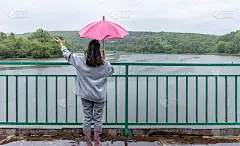 雨中桥上的一个女孩在伞下的背影。