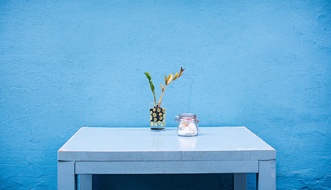  蓝色墙面 白色的桌子 文艺 放着玻璃瓶...