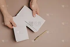 男子手里拿着一封模拟的信件或明信片，信封的背景是灰色的