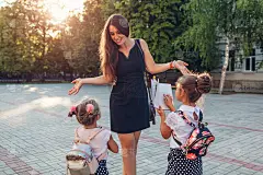 快乐的母亲会见她的孩子的女儿放学后在户外小学。孩子们给妈妈读书