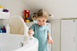 Little girl in bathroom cleaning bathtub with a brush.