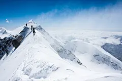 Climbers balancing in blizzard on a narrow mountain ridge