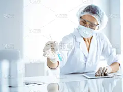 专业女科学家戴着防护眼镜，在实验室研究试管和试剂。医学和科学研究的概念