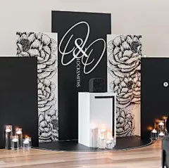 This may contain: a stage set up for a wedding with black and white floral wallpaper, candles and monogrammed backdrop