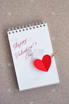 手写文字的笔记本:情人节快乐和用红纸剪出的一颗心
