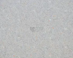 浅灰色花岗岩与橙色和黑色的小飞溅，抛光的天然石材表面的特写。