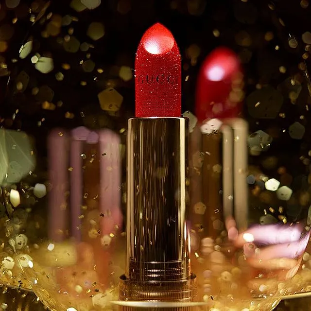 A tube of vivid red lipstick is shown in extreme closeup, its ...