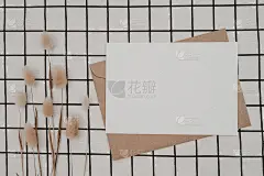 白色空白纸上的棕色纸信封兔尾干花和纸箱上的黑色布与黑白格图案。模拟水平空白贺卡。俯视图的工艺信封。