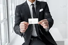 一个穿着西装拿着名片模型的人