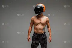 Athletic guy racer in helmet with naked躯干站在工作室的灰色背