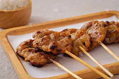叉烧猪肉或烤猪肉串放在盘子里，糯米饭放在碗里，是泰国街头小吃