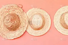 挂在粉红色背景的秸秆沙滩帽. 