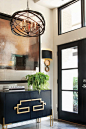 You don't always have to go big to go bold — sometimes, it's the smaller details that command attention. Though the large-scale art and stunning modern pendant draw the eye in this open entryway, the circular forms of the sconces and the bold abstract han