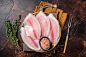 Raw fish fillet of tilapia in a plate with spices. Dark background. Top view