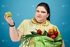 矮胖的女孩用水果和蔬菜打包