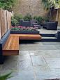 hardwood bench seat grey render block walls raised beds grey sandstone paving patio.