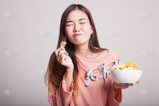 年轻的亚洲妇女吃薯片。