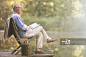 Older man reading book on dock at lake