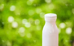 瓶子塑料白色的木材和树木模糊的散景背景在花园里。使用壁纸包装与产品形象。