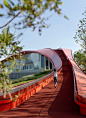 This may contain: a woman walking down a red walkway next to trees