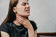 近距离观察不健康的年轻女子，颈部难以吞咽有不适或痛苦的感觉坐在家里的床上，不舒服悲伤的女孩遭受心绞痛
