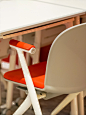 This may contain: an orange and white chair sitting at a table with two other chairs in the background