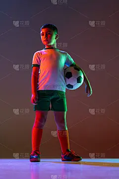 男孩的全身肖像，孩子，足球运动员在制服与球在霓虹灯梯度背景孤立。