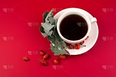 健康的玫瑰果茶在一个美丽的白色杯与干树枝在红色的背景。