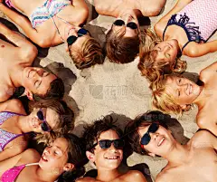 上面的一大群男孩和女孩, 快乐的朋友, 躺在沙滩上, 形成了他们的头圈