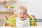 Happy baby girl in high chair eating创意图片素材 - Juice Images