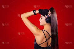 背影健美年轻性感的女人与长头发马尾辫手持耳机与手和美丽的指甲。