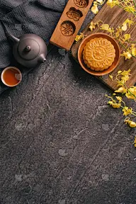 中秋节传统食品概念-美丽的月饼在黑石板桌上用茶，糕点模具，花。