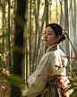 a woman in a kimono standing in a bamboo forest